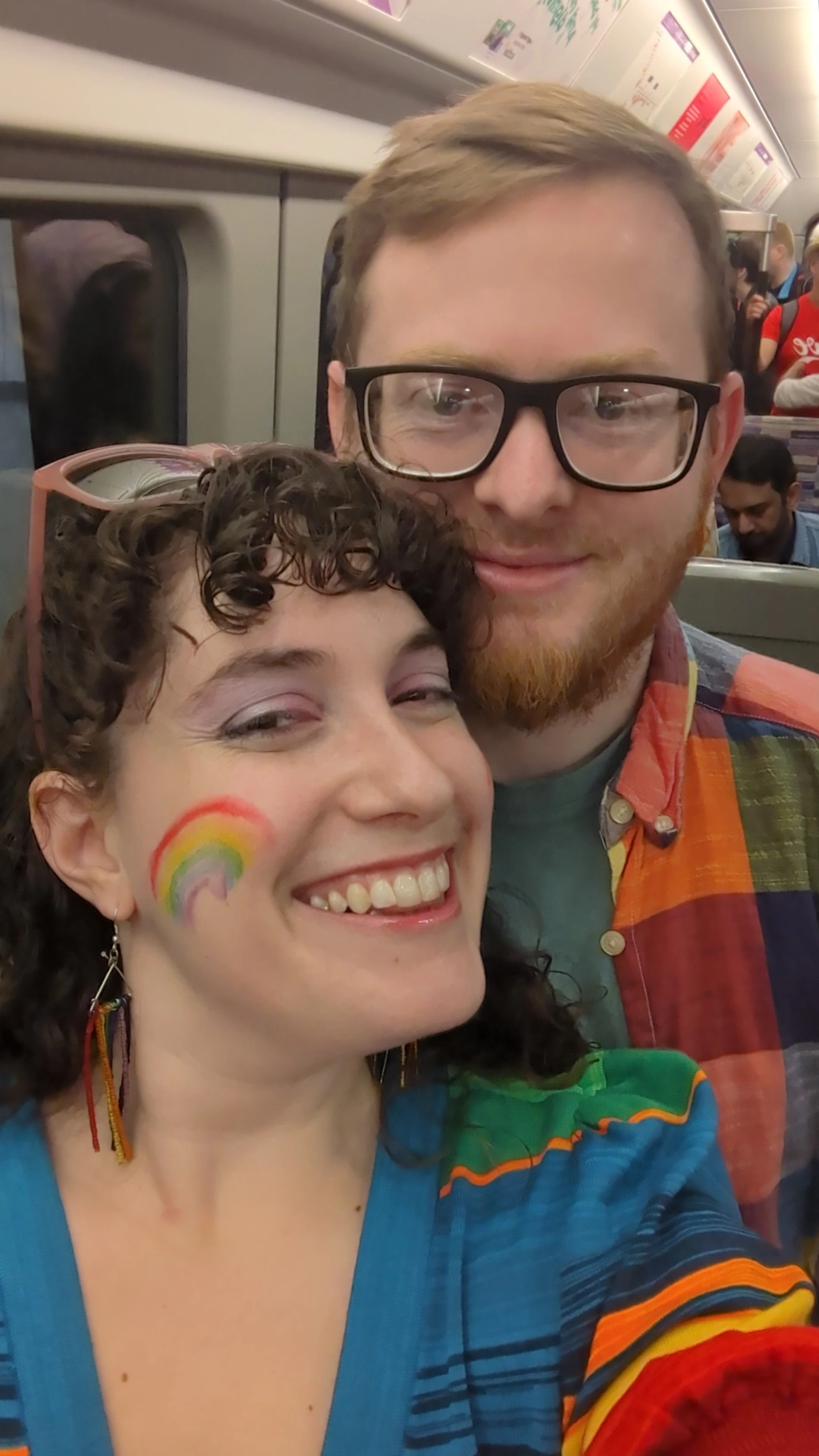 Becca and Q in London Pride attire on the tube